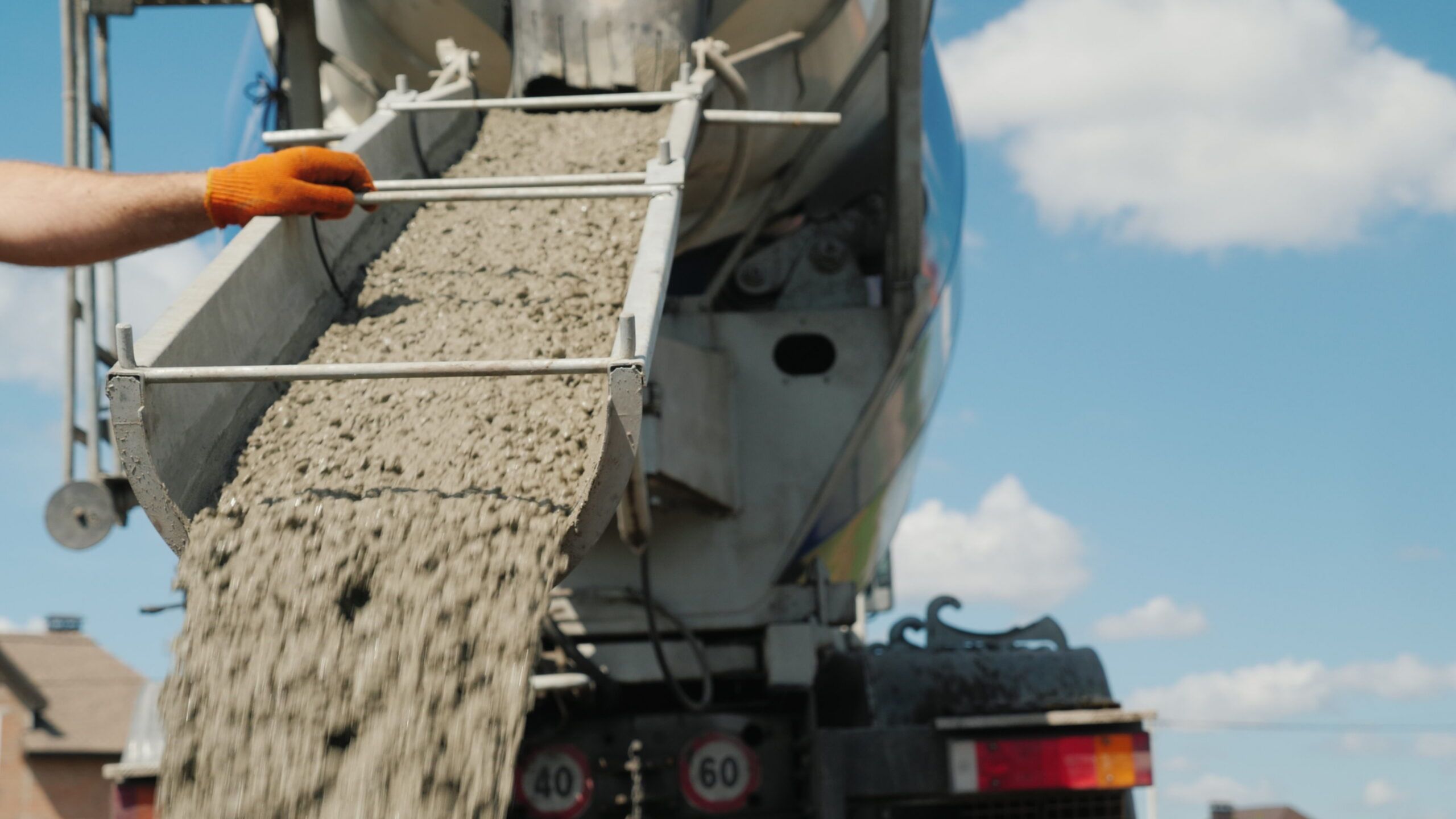 Work on pouring the foundation, the worker directs the chute from which the concrete flows